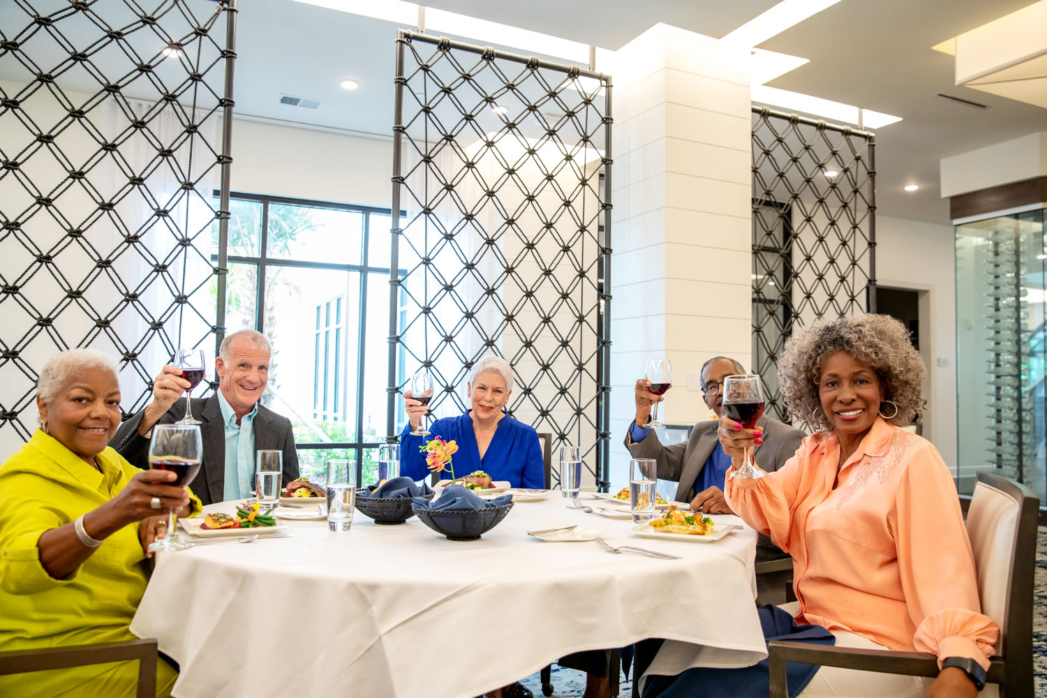 arbor terrace residents smiling holding wine glasses 