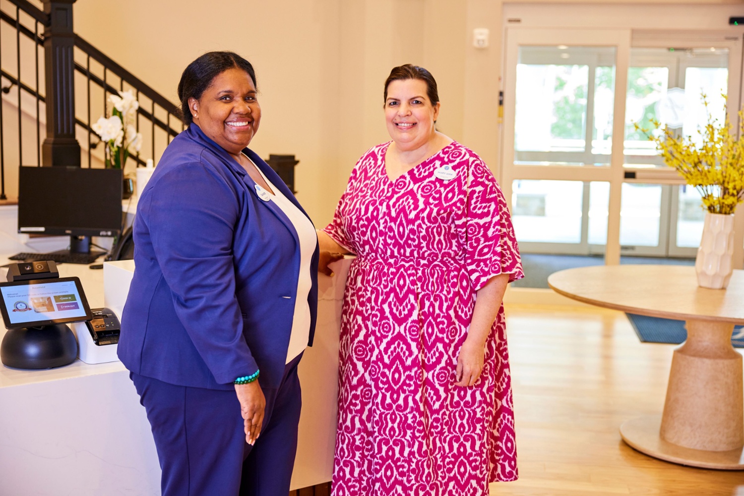 two female arbor terrace residents in a purple and pink dress smiling
